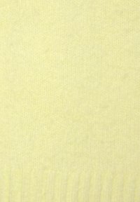 Helles gelbes Strickgewebe mit weicher Textur. Das Material wirkt glatt und weist am unteren Rand ein feines geripptes Muster auf.