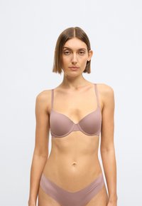 Svetlomauve podprsenka s nastaviteľnými ramienkami, tvarovanými košíčkami a bezšvovým dizajnom. Komplet tvorí so zodpovedajúcimi bezšvovými bikinkami.