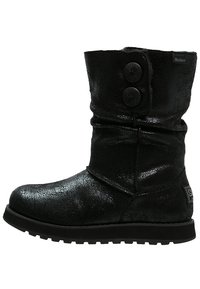 Czarne botki do połowy łydki o błyszczącej teksturze, z dwoma dekoracyjnymi guzikami z boku oraz solidną gumową podeszwą. Charakteryzują się luźnym fasonem.