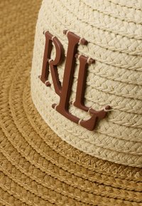 Široka slamnata kapa u bež i smešnom tonovima, sa smešnim "RL" logom na vrhu. Tekstura je tkan sa vidljivim detaljima šivanja.