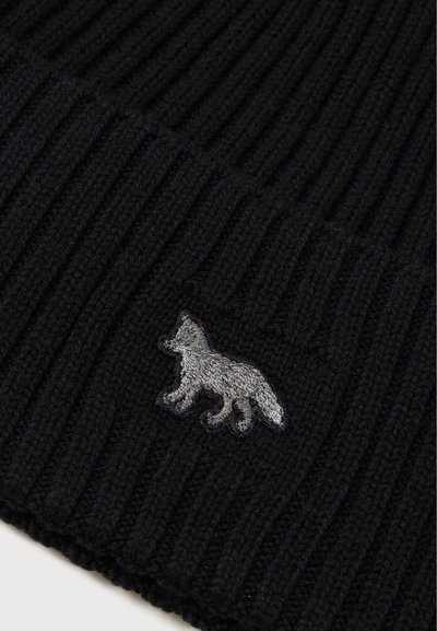 Černá pletená čepice s ribovanou strukturou, která obsahuje šedý vyšitý design lišky. Materiál vypadá měkce a pružně.