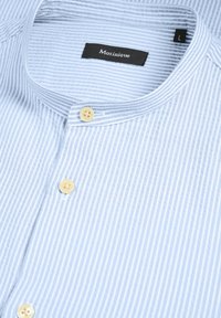 Lichtblauw gestreept shirt met een ronde kraag, voorzien van twee gele knopen en een zwart label. De stof lijkt zacht met een gladde textuur.