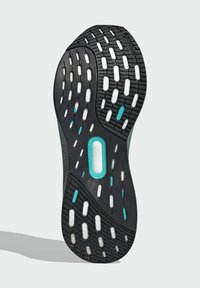 Black rubber shoe sole with a textured pattern. Features white and turquoise accents, including a central torsion system element.