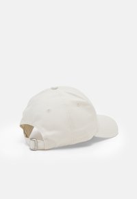 Cappello da baseball in cotone beige chiaro, con visiera curva, dettagli cuciti e fibbia metallica regolabile sul retro.