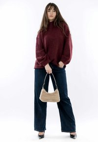 Burgundia ülisuur sviiter kõrge kaelusega, kombineeritud tumedate siniste teksadega. Käes beež faux fur käekott hõbedaste detailidega. Mustad kontsakingad.