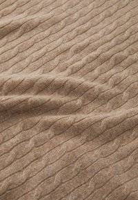 Beige knitted fabric with a textured cable pattern, featuring soft fibers, smooth surface, and gentle draping.