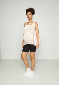 Top de alças listado em cores pastel, calções pretos e Ténis brancos. A carregar uma mala de ombro com padrão rosa. Design suave e ajustado.