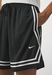Black athletic shorts with white stripes along the sides, featuring a textured fabric and a small white Nike logo on the lower front.