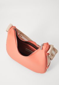 Borsa in pelle corallo con forma curva, chiusura con zip e tracolla in tessuto beige con logo. L'interno include una tasca piccola.