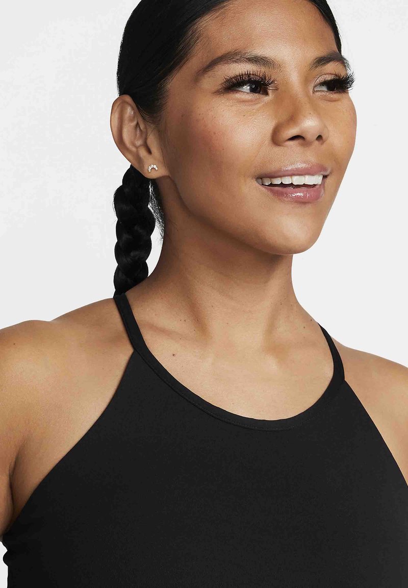 Top nero senza maniche con collo alto, texture liscia e spalline sottili. Il modello ha un'acconciatura con treccia lunga e orecchini a bottone piccoli.