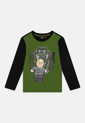 Grün-schwarzes Langarmshirt mit einem Lego-Figur, die einen Zauberstab hält, vor einem aufgedruckten Slytherin-Wappen auf der Vorderseite.