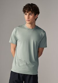 Camiseta atlética de manga corta de color verde claro con cuello redondo y tela texturizada. Presenta un ajuste relajado y un diseño minimalista.