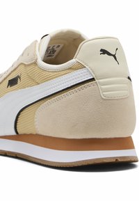 Beige sneakers med overdel i ruskind og mesh, hvid stribe og sorte detaljer. Har en brun gummisål og polstret krave.