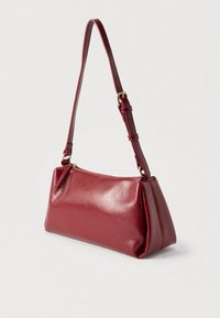 Sac à main en cuir rouge de forme rectangulaire, avec une bandoulière réglable et une fermeture éclair dorée. Texture lisse avec des détails subtils sur la surface.