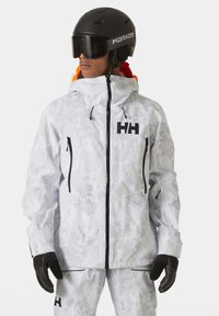 Veste blanche en neige avec un motif camouflage, des accents noirs et une fermeture éclair à l'avant. Comprend une capuche et deux poches zippées ; des gants sont également visibles.