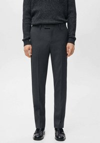 Szare, dopasowane spodnie garniturowe o gładkiej fakturze, wyposażone w szlufki na pasek, przednie kieszenie oraz slim fit. Noszone z ciemnym, dzianinowym swetrem.