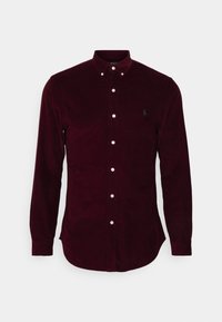 Camisa de pana burdeos de manga larga con cuello abotonado, botones blancos y sutil logo bordado en el lado izquierdo del pecho.