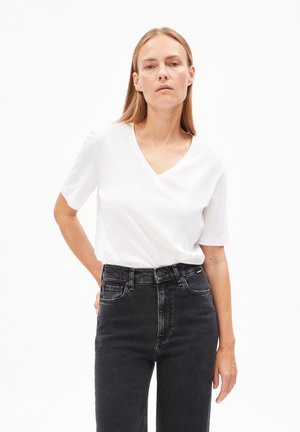 White V-neck t-shirt with short sleeves, made from soft fabric, paired with high-waisted black denim jeans for a casual look.