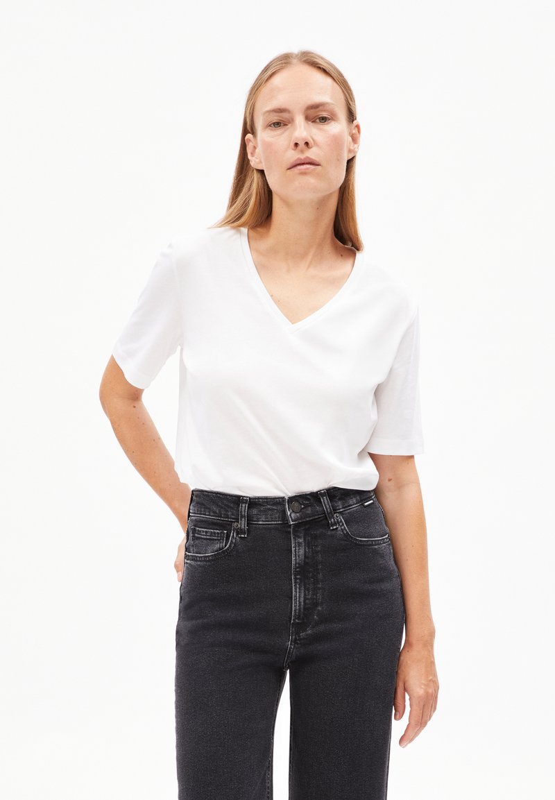 Witte V-hals t-shirt met korte mouwen, gemaakt van zachte stof, gecombineerd met hoge zwarte spijkerbroek voor een casual look.