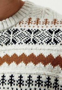 Gestrickter Pullover mit einem cremfarbigen Grundton und schwarzen, braunen sowie grauen geometrischen Mustern. Gerippter Ausschnitt und strukturierte, dicke Wolle.