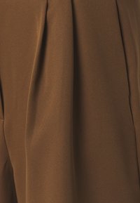 Brun tyg med synliga veck och en slät, något texturerad yta, som visar naturlig drapering och skuggning.