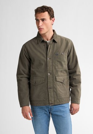 Olive green canvas jacket with a collared neckline, front button closure, and two large chest pockets. Worn over a light gray shirt.