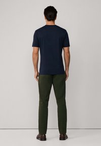 Marineblå t-skjorte med korte ermer, laget av bomull, avslappet passform. Kombinert med mørkegrønne chinos, slim fit, og brune lærsko.
