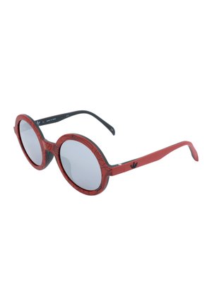 Occhiali da sole rotondi con montatura rossa decorata, terminali neri e lenti grigie riflettenti.
