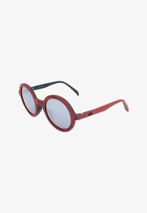 Occhiali da sole rotondi con montatura rossa decorata, terminali neri e lenti grigie riflettenti.