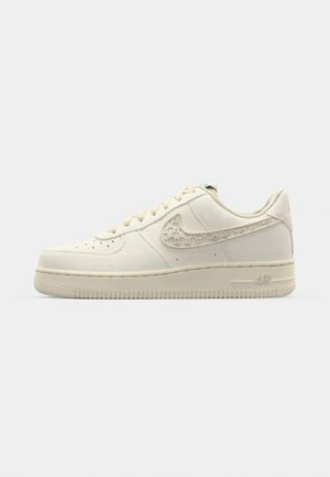 Nike Air Force 1 sneakers in off-white canvas, featuring a textured swoosh, round toe, flat laces, and a patterned rubber sole.