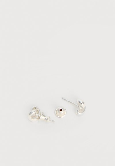 Ασημένια σκουλαρίκια με καρφίτσα, με μικρό σχέδιο κόμπου και πεταλούδα πίσω, τοποθετημένα σε λευκό φόντο.