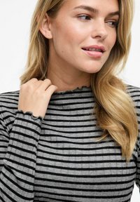 Långärmad, ribbad topp i grå och svarta ränder. Har en hög halsringning med scalloped kant och texturerat tyg.