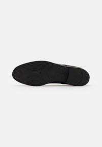 Semelle de sneaker noire avec une adhérence en caoutchouc texturé, présentant des motifs courbés et une finition lisse. Design plat sans logos ni accents visibles.