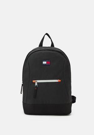 Black Tommy Jeans backpack with top handle, front zip pocket with orange accents, and logo patch on front center.