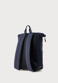 Σκούρο μπλε υφασμάτινο σακίδιο με καμπύλο σχήμα, επενδυμένη πλάτη, πλέγμα στην πλάτη και ρυθμιζόμενους ιμάντες. Διαθέτει επάνω λαβή και πλαϊνή τσέπη.