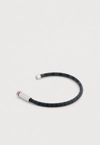 Μαύρο κυκλικό βραχιόλι με μεταλλικές λεπτομέρειες, που διαθέτει υφή και μοτίβο λογότυπου. Τα άκρα είναι ασημένια με λεπτομερή χάραξη.