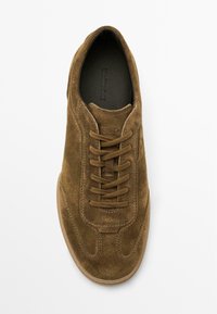 Sneaker in suede marrone con punta rotonda, caratterizzato da chiusura con lacci e suola in gomma testurizzata. L'interno presenta una fodera scura.