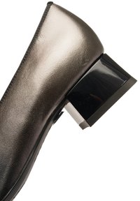 Black and metallic flat shoe with a pointed toe and a square block heel. Smooth leather upper with a glossy, textured accents on the heel.