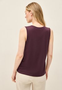 Débardeur bordeaux foncé sans manches avec un col rond, fabriqué en tissu doux. Le dos présente une texture subtile et une coupe décontractée.