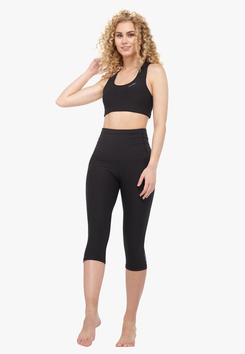 Schwarzes sportliches Crop-Top und hochgeschnittene Leggings aus dehnbarem Material. Das Top hat einen runden Ausschnitt; die Leggings haben eine glatte Oberfläche.