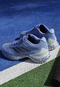 Light blue athletic shoes with black stripes and textured accents, featuring a leopard print sole and reinforced heel design.