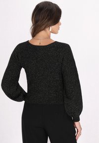 Maglione nero con un motivo a maglia testurizzato, orlo a costine e maniche lunghe a sbuffo. Il materiale ha una leggera lucentezza metallica.