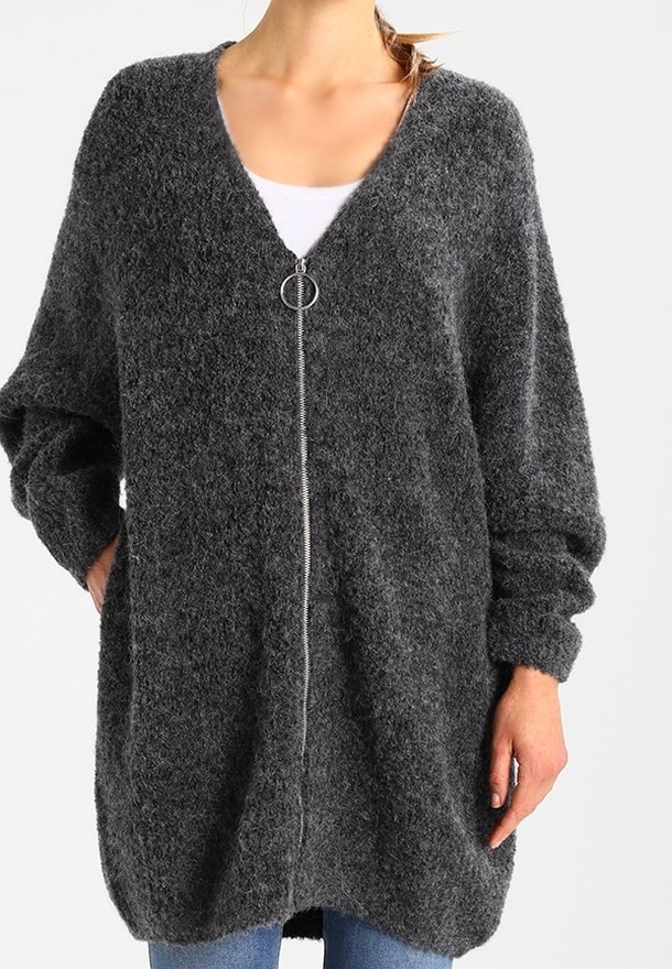 Kolsvart, fluffig oversized cardigan med V-ringning, framdragkedja och långa ärmar. Mjuk textur med avslappnad passform.