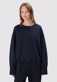 Donkerblauw oversized sweatshirt met een ronde hals, verlaagde schouders en geribbelde manchetten. Zachte stof met een gladde textuur.