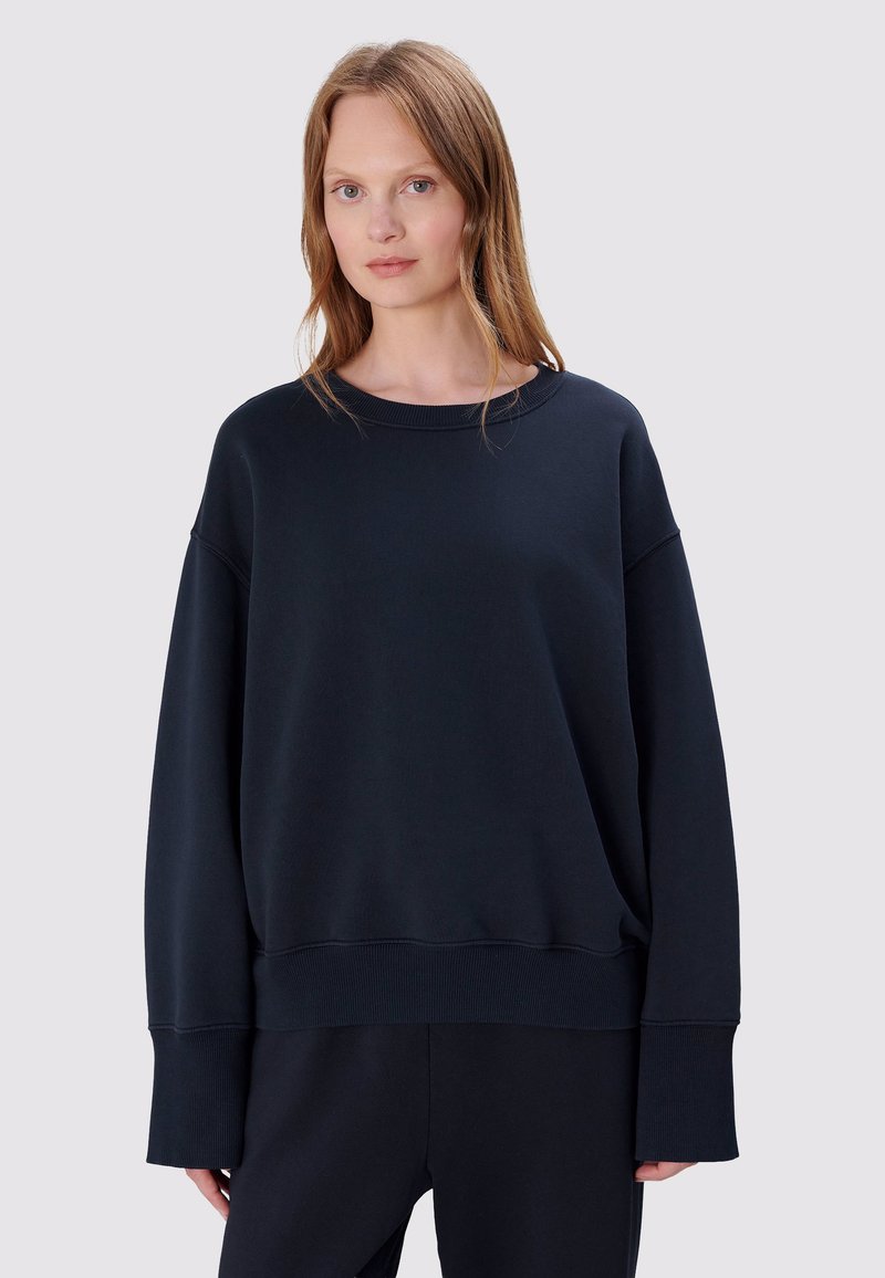 Donkerblauw oversized sweatshirt met een ronde hals, verlaagde schouders en geribbelde manchetten. Zachte stof met een gladde textuur.