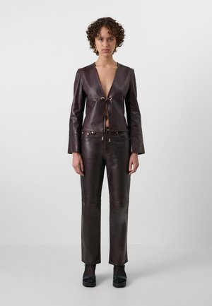 Brown leather cropped jacket with a deep V-neck and tie front, paired with matching leather pants. Features gold-tone hardware accents.