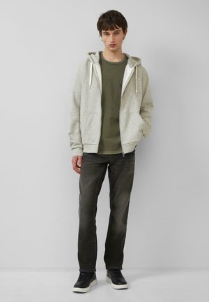 Light gray zip-up hoodie with a white lining, layered over an olive green t-shirt, paired with dark gray jeans and black sneakers.