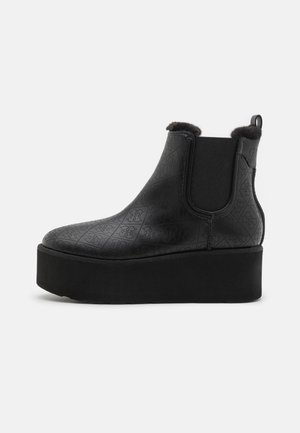 Black platform Chelsea boot with quilted pattern, elastic side panels, faux fur lining, and pull tab at the back.