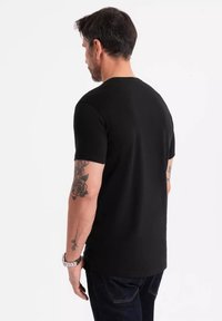 Černé tričko s krátkým rukávem vyrobené z bavlny, s kulatým výstřihem a slim fit, zobrazené zezadu.