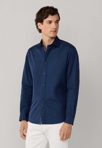 Granatowa koszula z długim rękawem z kołnierzykiem zapinanym na guziki, wykonana z gładkiego materiału, z delikatnym połyskiem i prostym wzornictwem.
